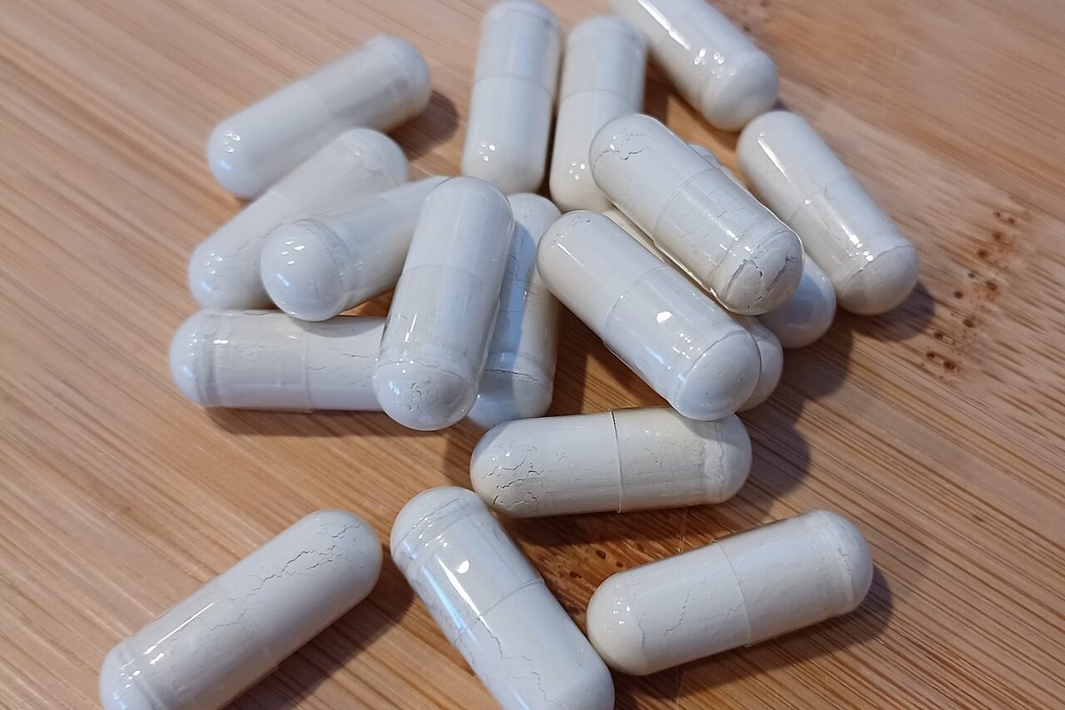 Powder-filled supplement capsules on a wooden table, the form most ashwagandha extracts are sold in