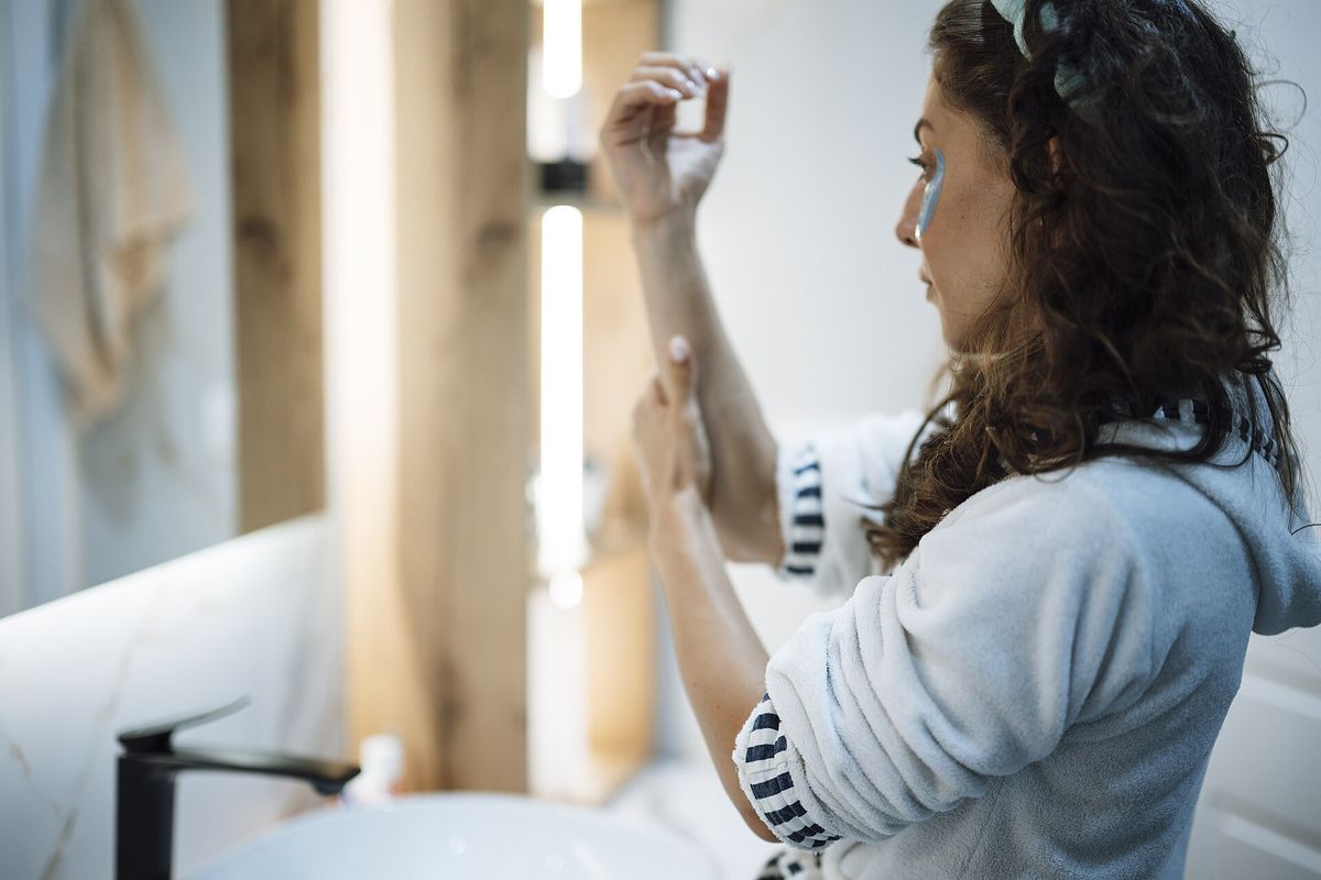 Woman applying moisturiser to her arm after a bath