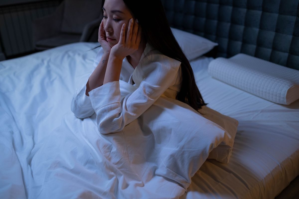 Woman sitting awake in bed at night, unable to sleep