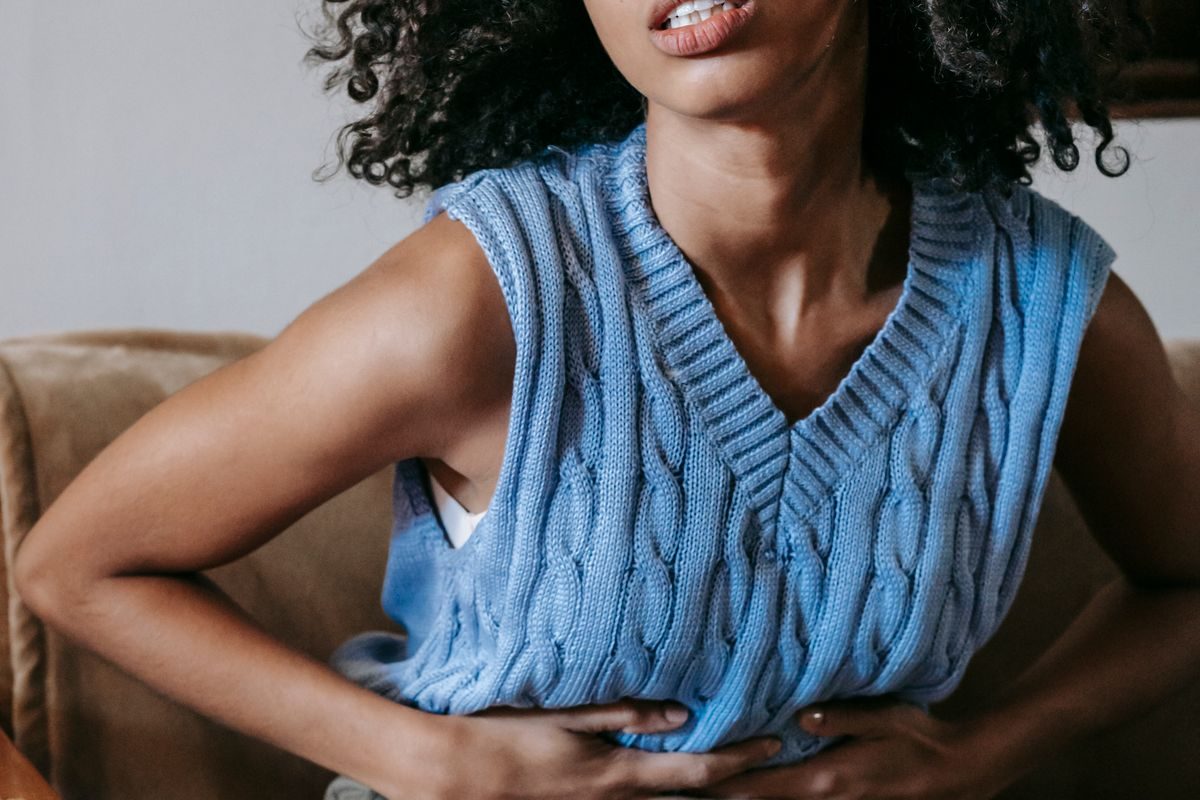 Young woman holding her lower abdomen with period cramps