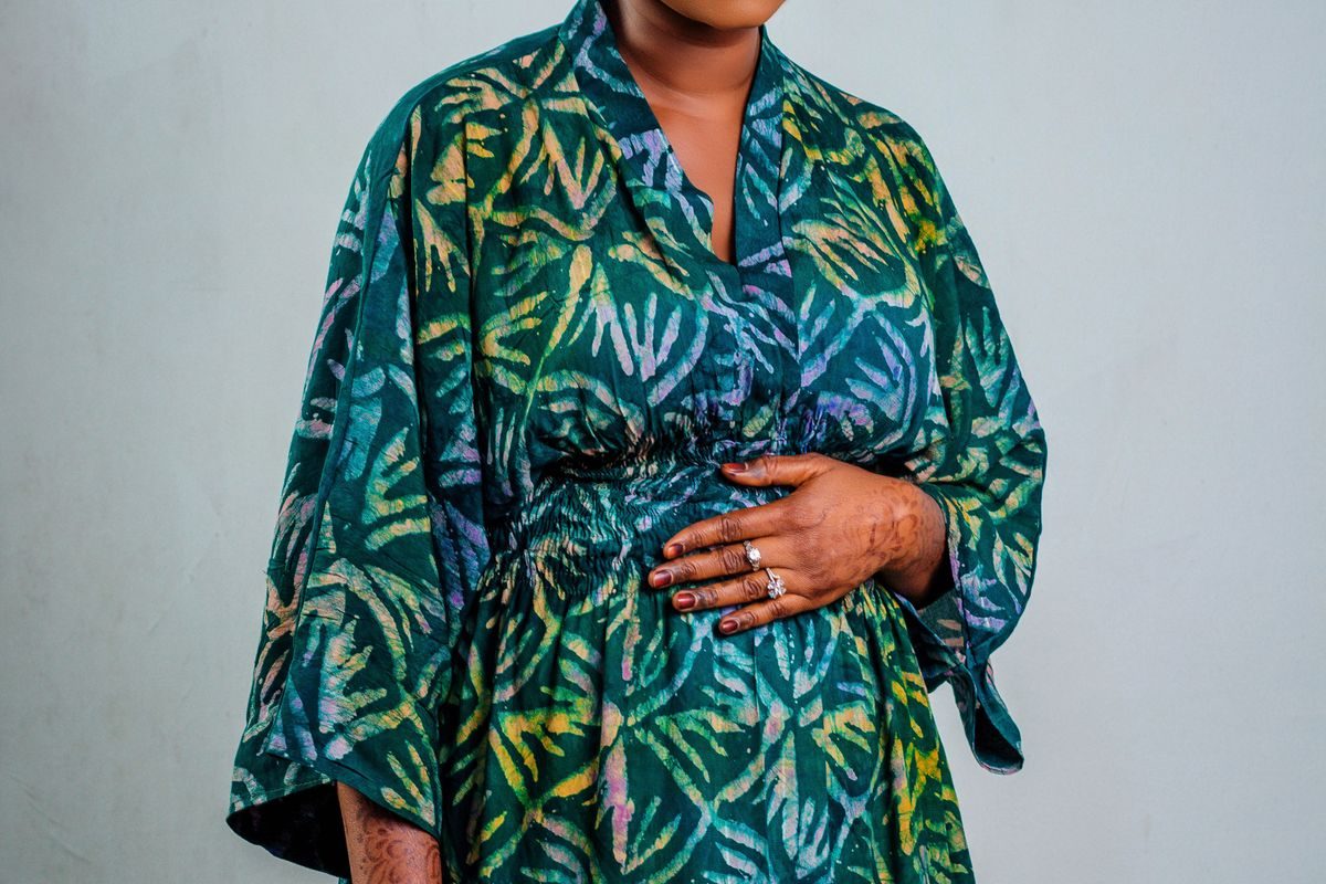 Pregnant woman in a patterned robe resting her hands on her belly