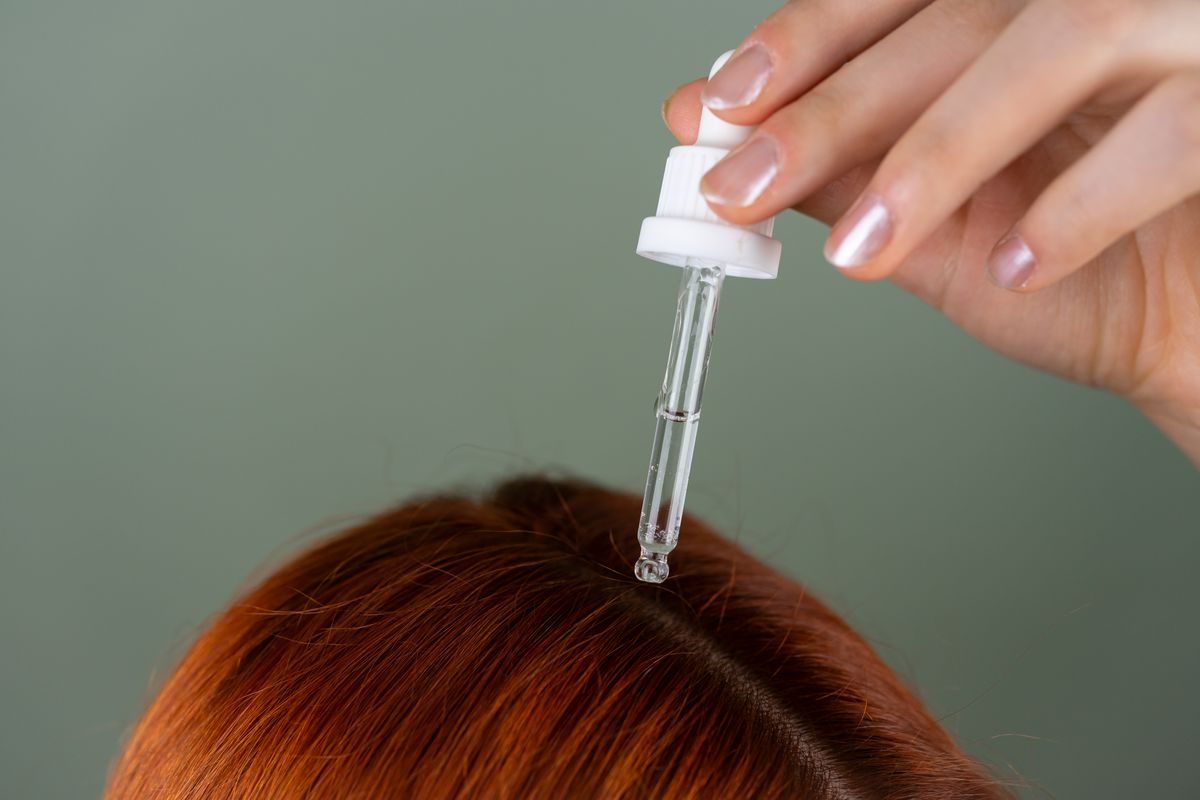 Herbal oil being applied to the scalp with a dropper