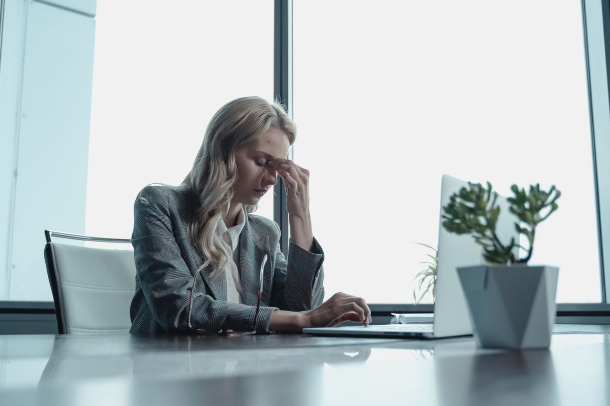 Stressed woman at her desk holding her head in her hands