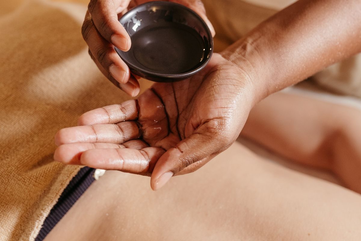 Therapist pouring warm medicated oil into her palm before an Ayurvedic massage